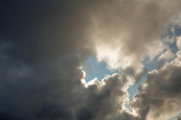 The sun and clouds on the blue sky. Cloudy weather with cumulus, dark clouds. Autumn day. A strong wind blows, the pressure is low, the threshold of rain.