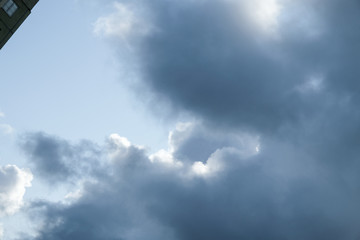 The sun and clouds on the blue sky. Cloudy weather with cumulus, dark clouds. Autumn day. A strong...