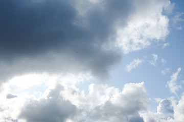The sun and clouds on the blue sky. Cloudy weather with cumulus, dark clouds. Autumn day. A strong wind blows, the pressure is low, the threshold of rain.