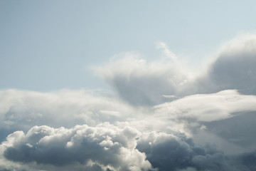 The sun and clouds on the blue sky. Cloudy weather with cumulus, dark clouds. Autumn day. A strong...