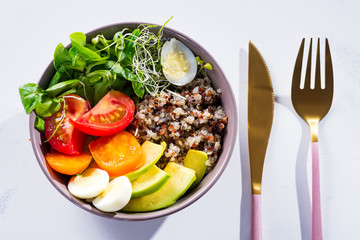 Fresh healthy salad with quinoa, cherry tomatoes and mixed greens, avocado, egg and micro greens on marble background top view. Food and health. Superfood meal. Clean eating. Healthy lifestyle