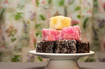 Colourful Australian dessert Lamingtons stacked and served on a cake stand 