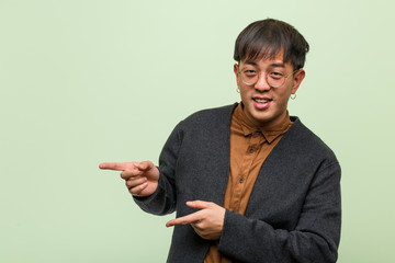 Young chinese man wearing a cool clothes style against a green background