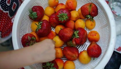 Close-up. A children hands in fist over strawberry in plate. Healthy breakfast.