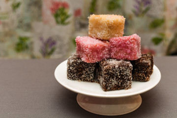 Colourful Australian dessert Lamingtons stacked and served on a cake stand 
