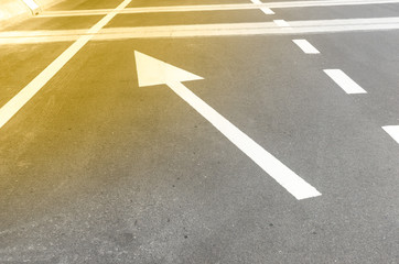 The white arrow symbol on an asphalt road, indicating direction of traffic o forward and turn left....