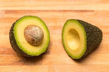 Fresh avocado  cut the "wrong" way on a chopping block.