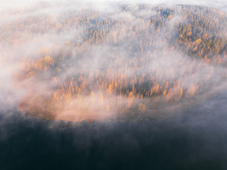Autumn landscape. Lake and forest covered in fog at dawn. Aerial scenery