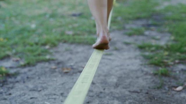 Female Feet On Slack Line Tight Rope. Balancing on a slack line. CLOSE UP: Unrecognizable woman slacking and balancing on a slackline, 4k stock footage