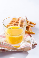 Orange juice and belgian or french waffles for breakfast on light background