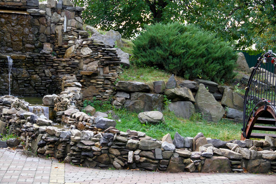 a beautiful mini-waterfall, accompanied by green plants next to it, created by the iridescent pool water