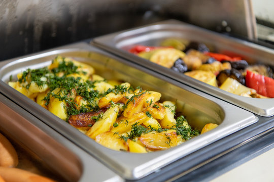 Potato wedges, sausages and grilled vegetables in marmite on hotel breakfast