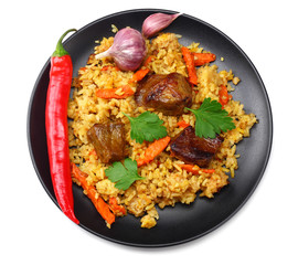 pilaf with meat and chili pepper on black plate isolated on white background. top view
