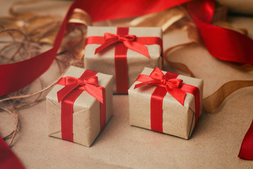 Set of gift boxes wrapped in craft paper and tie red satin ribbon. Christmas presents. Holiday mood. New year decor.