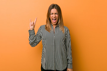 Young authentic charismatic real people woman against a wall showing a horns gesture as a...