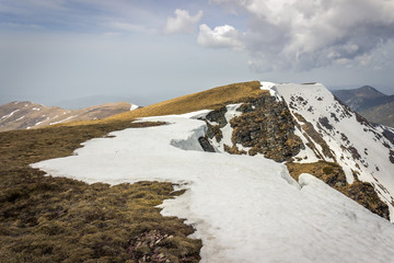 Dramatic, moody view from a Midzor summit, the highest peak of Old mountain, during transition period between winter and spring with some remaining snow and sunlit highlands