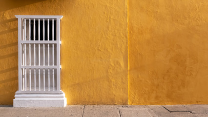 Colonial facade with ocher or yellow wall and window with white balusters, ideal for background,...