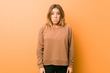 Obraz premium Young authentic charismatic real people woman against a wall shrugs shoulders and open eyes confused.