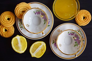 Cups made for tea, lemon and sweets on a black background.