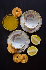 Cups made for tea, lemon and sweets on a black background.