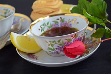 Fresh fragrant tea with lemon in a beautiful Cup on a black background.