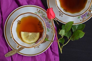 Fresh fragrant tea with lemon in a beautiful Cup on a black background.