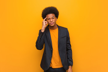 Young business african american man over an orange wall thinking about an idea