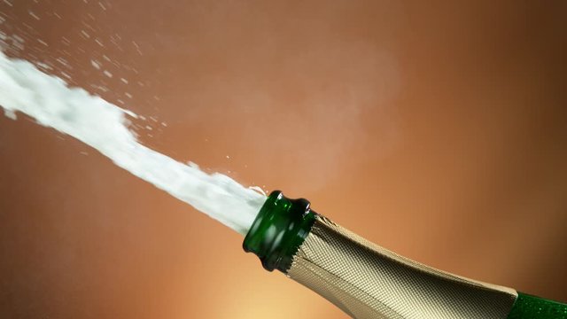 Super slow motion of Champagne explosion with flying cork closure, opening champagne bottle closeup.