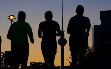 Silhouette of early morning joggers running with the Fernsehturm in the background