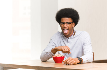 Young black man having a breakfast funnny and friendly showing tongue