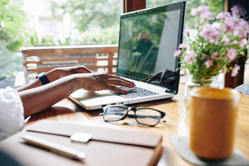 Close-up of African businesswoman sitting at the table and working on laptop at home