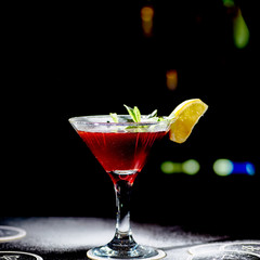 Red cocktail similar to a Margarita covered with powdered sugar is on the bar.
