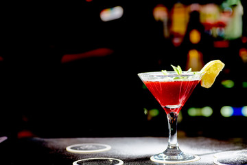 Red cocktail similar to a Margarita covered with powdered sugar is on the bar.