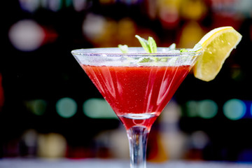 Red cocktail similar to a Margarita covered with powdered sugar is on the bar.