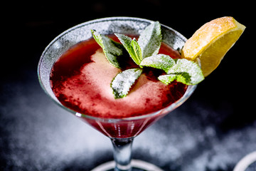 Red cocktail similar to a Margarita covered with powdered sugar is on the bar.