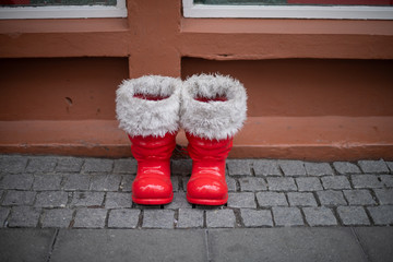Red santa boots with white fur on sidewalk