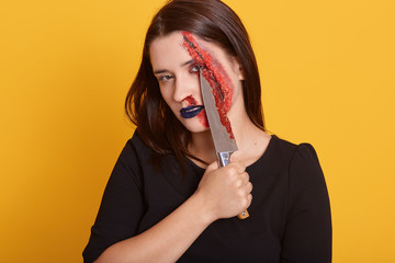 Image of student girl with blood on her face, has hurt, posing with knife in hand, holding chopper...