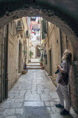 A woman is standing in an alley in Dubrovnik.