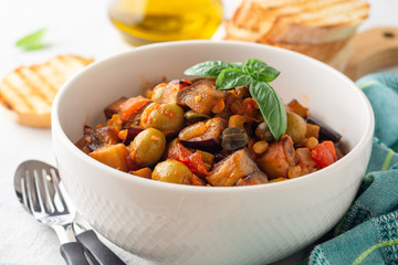 Traditional sicilian eggplant dish Caponata in bowl on concrete background. Selective focus.