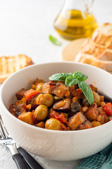 Traditional sicilian eggplant dish Caponata in bowl on concrete background. Selective focus.