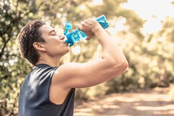Fit sporty male drinking from bottle of water. 
