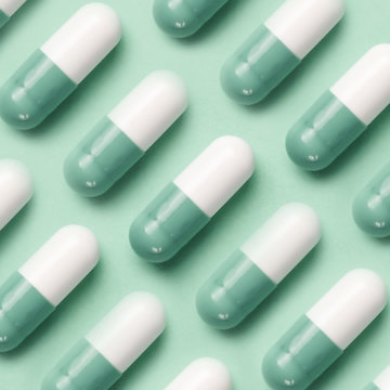 Medical pattern made with pills on mint background. Pharmaceutical medicine pills, tablets and capsules on mint background. Flat lay. Medicine concepts. Minimalistic abstract concept. Neo mint color