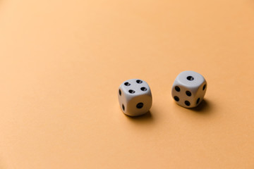 White gaming dice on orange background. Top view. Flat lay. Copy space. Game of chance concept. Close-up. Pastel colors