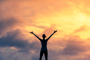 Woman with arms raised to the sunset feeling inspired 