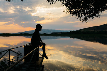 Silhouette of a model infront of a lake at sunset time, there are lots of reflections of clouds and...