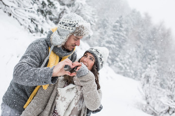 Pärchen macht Herz mit Händen im Winter Urlaub