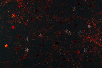 Red and silver sparkles on black backdrop. Holiday concept.