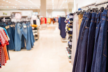 Trousers hang on rails in modern clothes shop