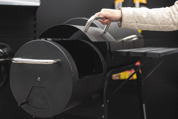 A young woman is choosing a new barbecue oven in store.