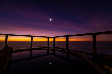 Fototapeta na wymiar An amazing an idyllic view a wooden hot tub waiting us for some relaxation time during sunset and twilight before an awe night sky with a small crescent moon. A leisure activity at Chilean coastline